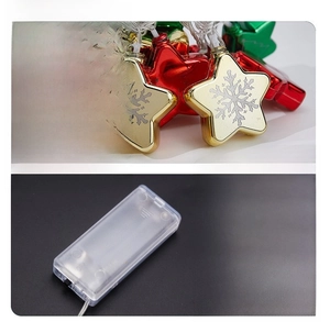 Close-up of golden and red LED star lights with Merry Christmas engraving and battery box