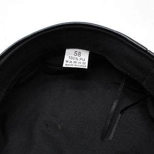 Detail view of black faux leather navy hat showing the 100% PU material label and inner lining