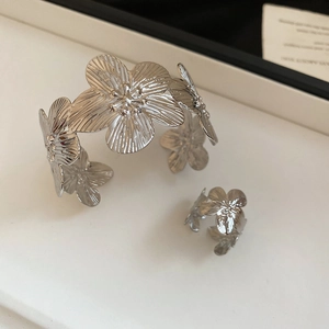 Detailed macro view of silver flower bracelet and matching ring with brushed metal textures