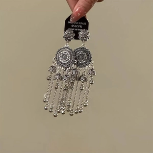 Detail of vintage silver boho earrings featuring mandala patterns and bell tassels