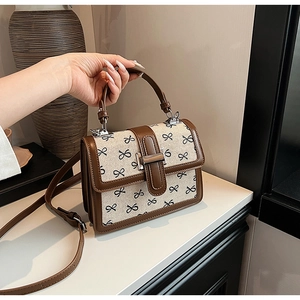 Dettagli di una borsa a mano marrone e beige con stampa a fiocchi e tracolla rimovibile