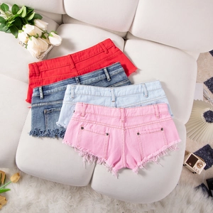 Flachbild von bunten Jeans-Shorts mit Fransen auf weißem Sofa mit Rosen-Deko