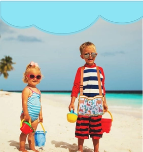 Kids dinosaur mesh beach bag with orange straps worn by a child on a sunny beach