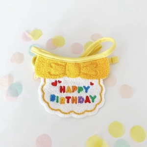 Close-up of yellow dog birthday bib with HAPPY BIRTHDAY embroidery and colorful bow