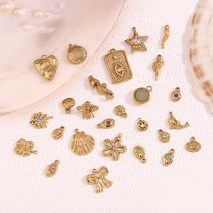 Detailed flat lay of 14K gold-plated shell, seahorse, and smiling face jewelry charms