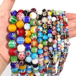 Hand holding colorful Millefiori glass beads of various sizes for DIY jewelry making
