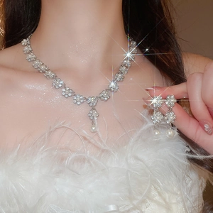 Detail of floral necklace and pearl earrings set with sparkling stones on a model
