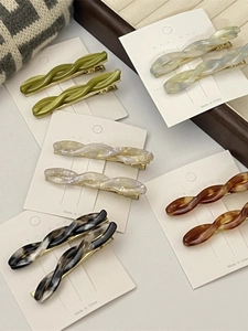 Close-up of acetic acid twisted hair clips in green blue amber and marble patterns