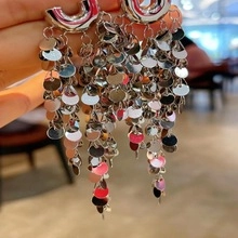 Silver long tassel earrings with multi-layered round metallic sequins in hand view