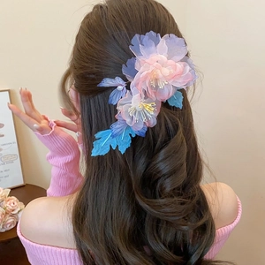Detail of gradient pink and purple acrylic petal hair clip worn on a low bun hairstyle