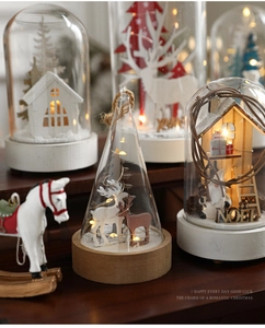 Detail of festive glass dome with warm LED lights and miniature reindeer snow scene