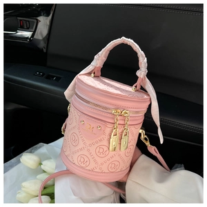 Pink embossed cylinder bag with chain tassels and silk scarf handle on car seat