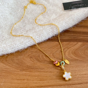 Macro shot of a floral beaded gold necklace draped over a white knitted sweater