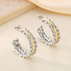Macro detail of twisted rope hoop earrings in dual-tone gold and silver steel finish