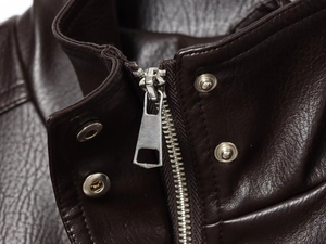 Close-up of the silver metal zipper and snap button on dark brown faux leather jacket