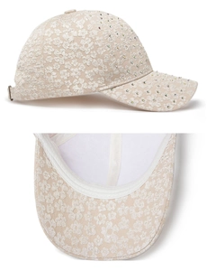 Detail of floral lace embroidery and rhinestones on a beige women's baseball cap
