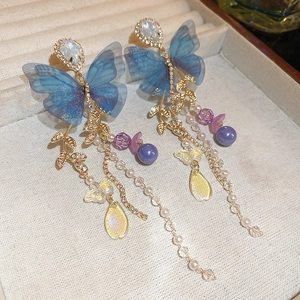 Close-up of blue butterfly tassel earrings with mesh wings and crystal beads in a gift box