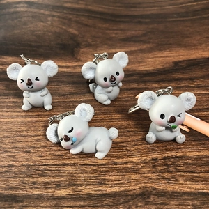 Detail showing four cute resin koala charms in different poses on a wooden background