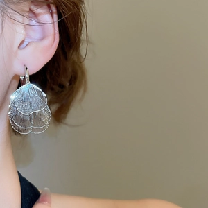 Détail macro de boucles d'oreilles en maille argentée au design floral à couches