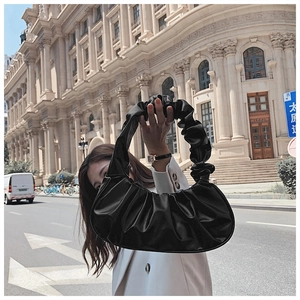 Detail of black pleated cloud bag with soft PU leather texture and shoulder strap