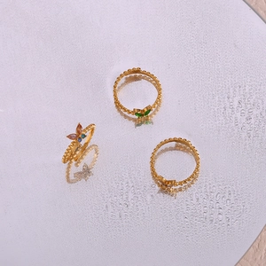 Makro-Detail goldener Schmetterlingsringe mit bunten Edelsteinen auf reflektierender Fläche