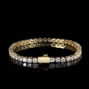 Macro shot of gold tennis bracelet with white zircons on black reflective background