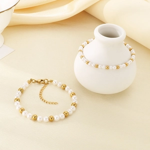 Elegantes Armband aus Goldperlen und Perlen auf Seidenstoff mit Keramikvase