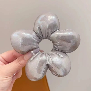 Close-up of a metallic silver oversized flower hair tie with 3D sponge padding