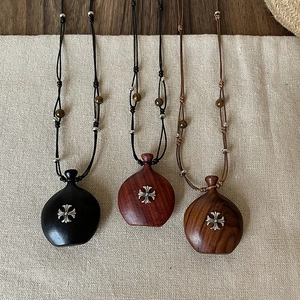 Trois colliers avec pendentifs en bois en forme de cœur et croix métalliques sur lin