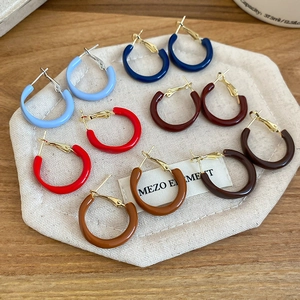 Detailed set of six colorful enamel C-shape hoop earrings on a natural linen bag