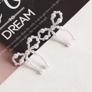 Detail of handcrafted white pearl bow earrings with intricate woven texture and elegant style