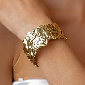 Detailed view of wide gold open cuff bracelet with irregular hammered metal texture