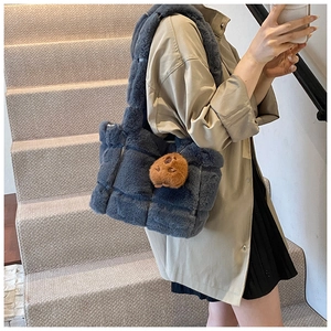 Detail of grey plush woven shoulder bag with a cute brown bear charm accessory