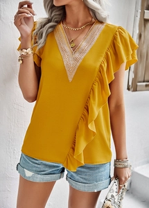 Detail of yellow V-neck shirt with white lace trim and asymmetrical ruffled front