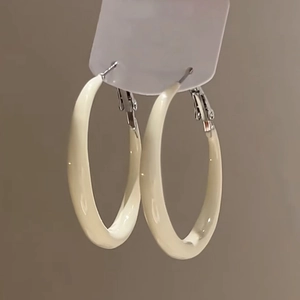 Close-up of cream-colored resin hoop earrings on a display card with silver pins
