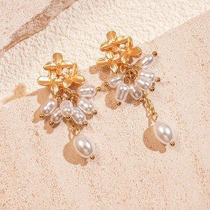 Gros plan de boucles d'oreilles fleurs dorées avec d'élégantes franges en perles
