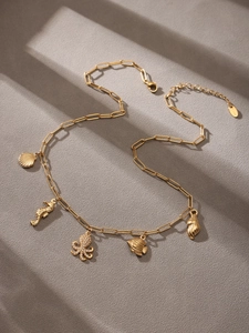 Detailed view of gold chain necklace featuring seashell and crystal octopus charms