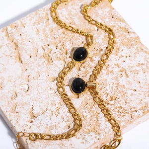 Detail of 14K gold plated Figaro chain necklace with black oval natural stone charms
