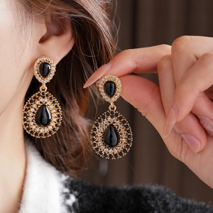 Gros plan de boucles d'oreilles vintage dorées avec strass noirs et clairs sur modèle