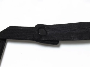 Close-up of black twill fabric texture and matte snap button on a halter midi dress