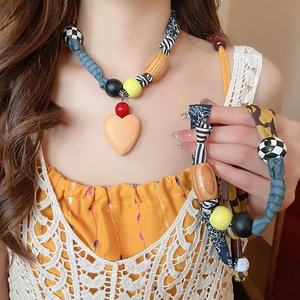 Détail du collier de perles bohème avec tissu, bois et un pendentif en forme de cœur orange