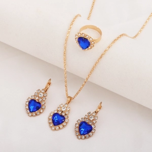 Close-up of golden jewelry set featuring heart-shaped blue gemstones and crystal accents