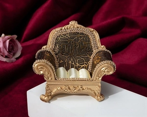 Miniature gold sofa jewelry stand with white satin cushion on a red velvet background