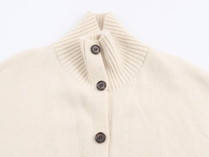 Gros plan du cardigan beige à col montant avec des boutons foncés et texture tricotée