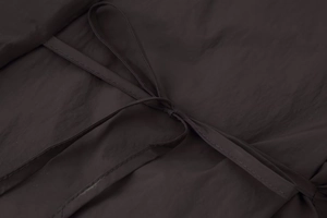 Detailed close-up of deep brown quilted fabric texture with premium tie-up drawstring detail