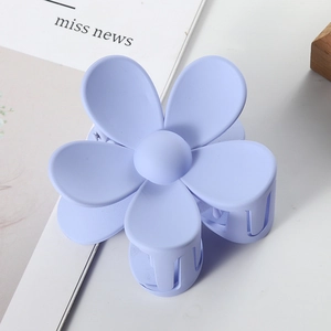 Detail view of the matte purple floral hair claw clip on a stylish magazine surface