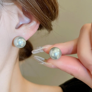 Close-up of minimalist silver gray pearl stud earrings worn and held for size scale