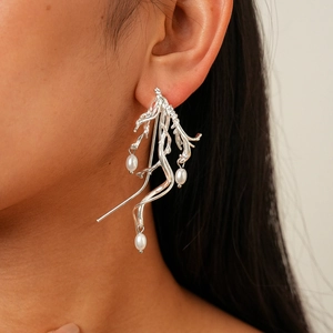Detailed close-up of irregular silver twig earrings with elegant white teardrop pearls