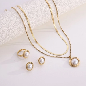Detail of gold necklace set with pearls featuring double layer chains and matching ring