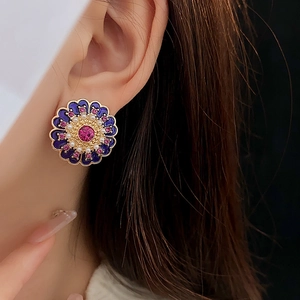 Close-up of vintage flower earrings with purple enamel, pink gemstones and white pearls